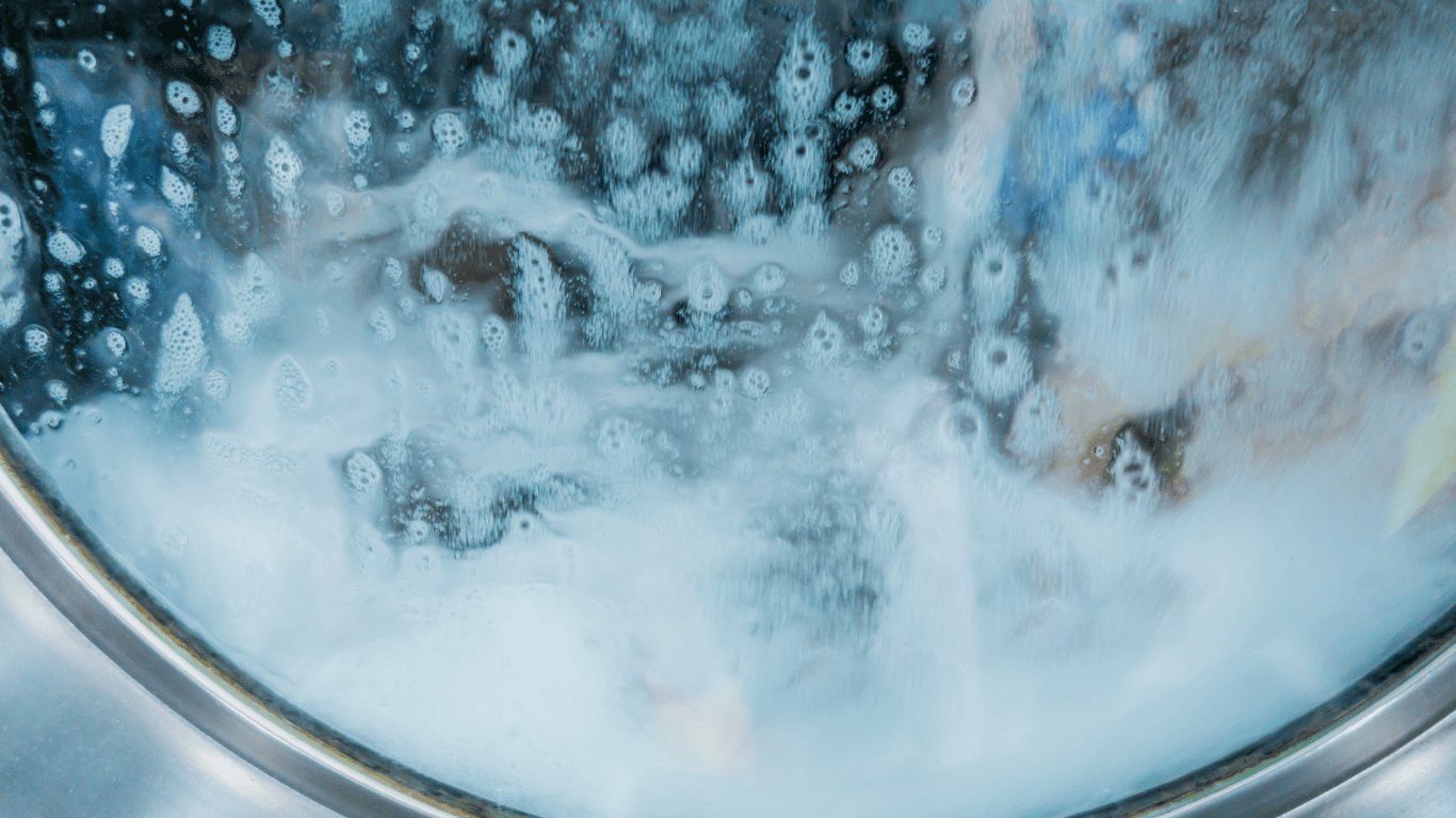 Acqua e schiuma dentro l'oblò di una lavatrice